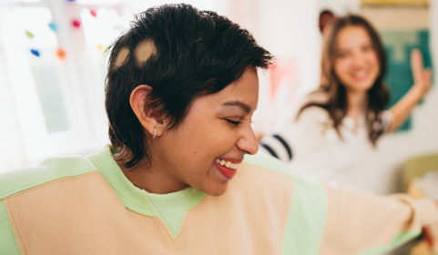 Adolescent girl with severe alopecia areata after hair regrowth smiling with a friend